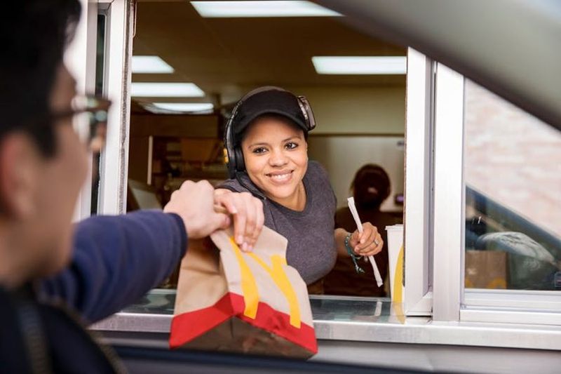 A crew member handing a bag through the drive-thru window